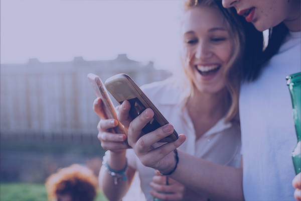 Two teen girls laughing at mobile phones content