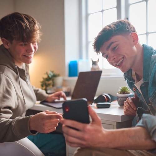 Teenagers laughing at image on mobile phone